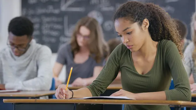 A mixed race teenage girl is taking a high school standardized test in class.