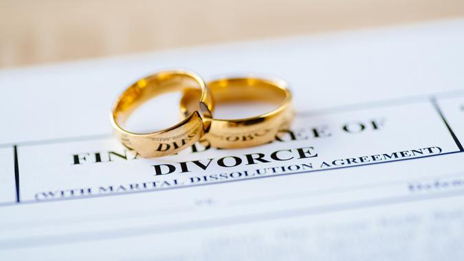 Two broken golden wedding rings divorce decree document. Divorce and separation concept