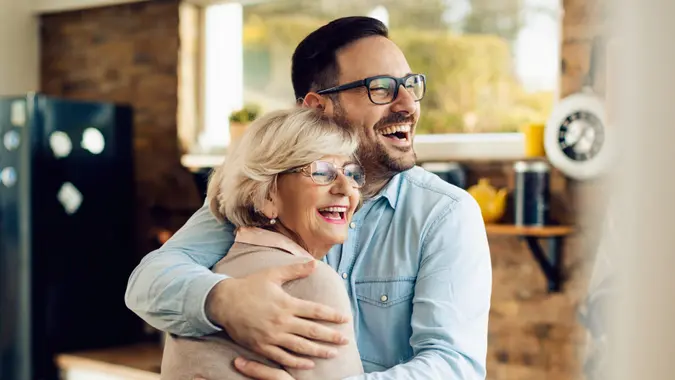 Cheerful senior woman embracing her mid adult son who came to visit her at home.