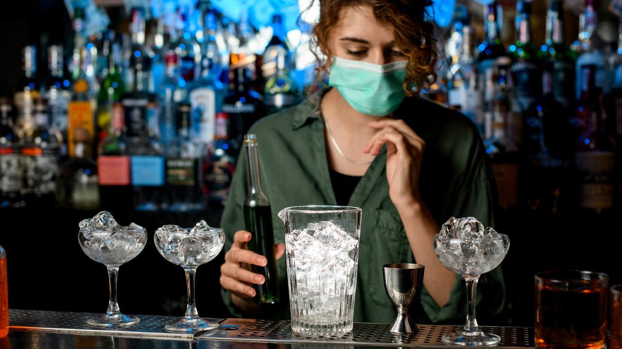 bartender girl in medical mask preparing to make cocktail.