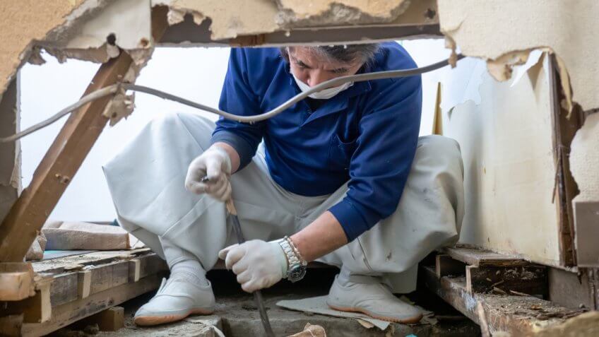 Japanese construction worker checking the under floor space with crowbar.