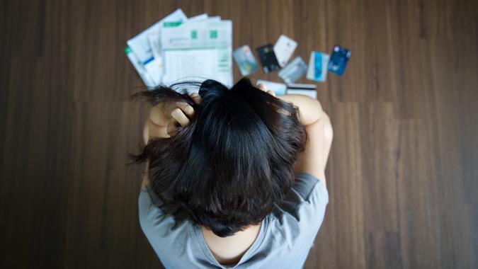 Woman with credit cards and bills spread on the floor