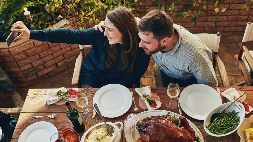 Cropped shot of a couple taking a selfie while eating outside.
