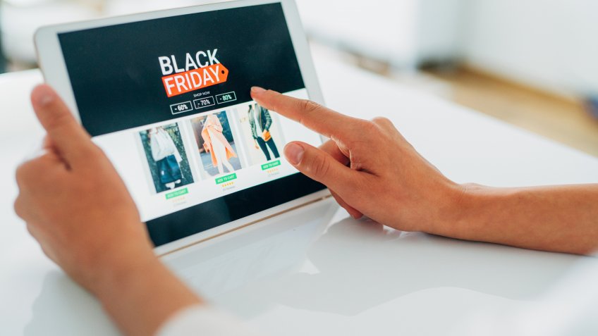 Close-up shot of a young woman holding a digital tablet and shopping online on Black Friday at home.