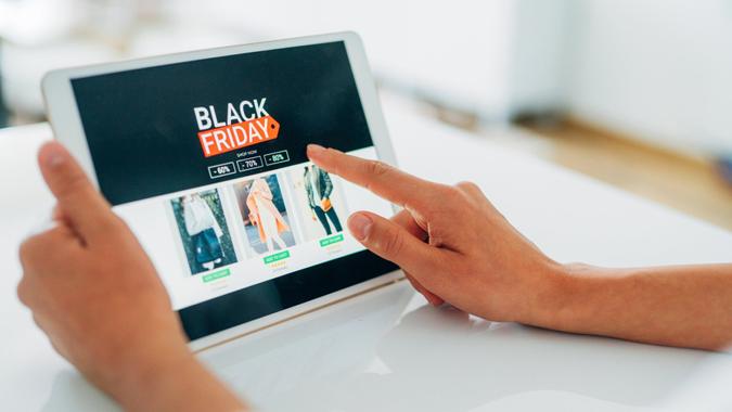 Close-up shot of a young woman holding a digital tablet and shopping online on Black Friday at home.