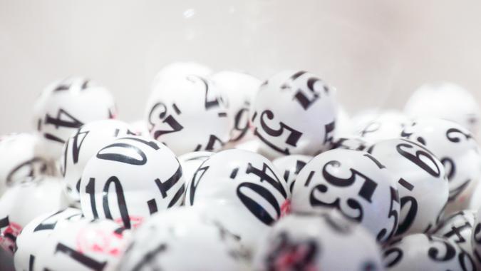 Many white lottery balls with black numbers on them are close together.