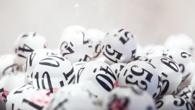 Many white lottery balls with black numbers on them are close together.