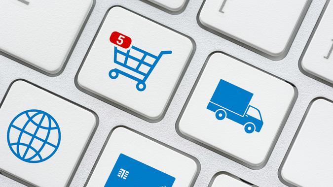 Online shopping / ecommerce and retail sale concept : Shopping cart, delivery van, credit card, world globe logo on a laptop keyboard, depicts customers order things from retailer sites using internet.