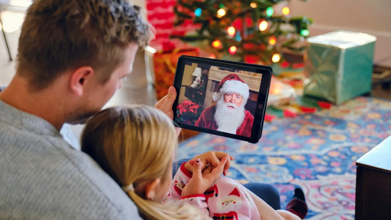 A father and daughter, talking to Santa Claus on a computer video conference call.