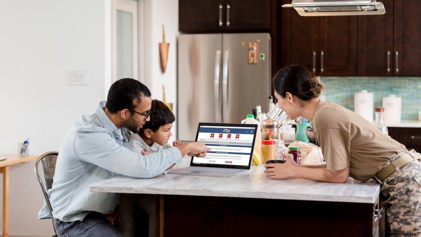 A mid adult dad explains the voting process to his young son as the man prepares to vote online.