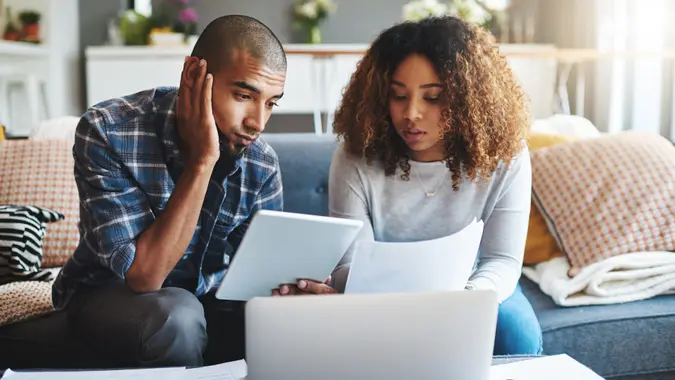 Cropped shot of a stressed young couple sitting together and using a laptop to go over their financial paperwork.