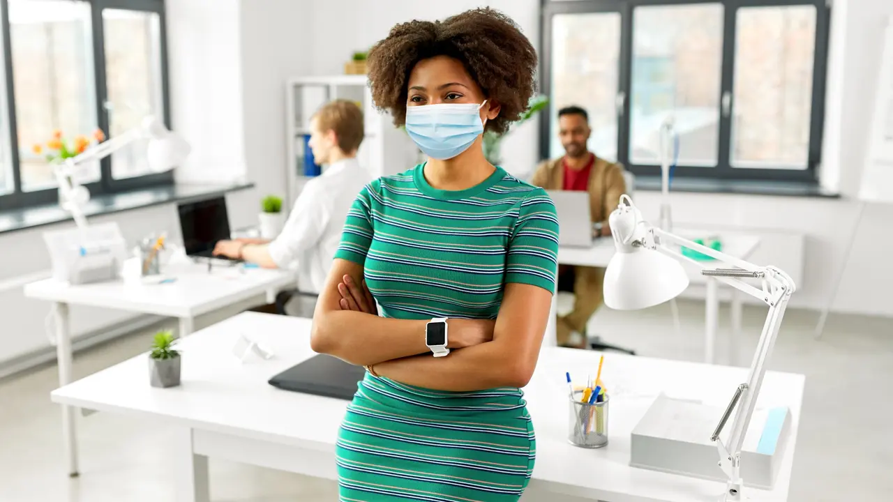 Woman with smart watch in medical mask at office stock photo
