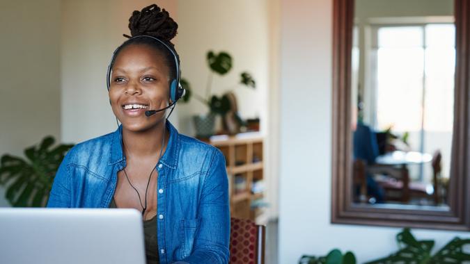 Shot of a young woman using a laptop and headset while working from home.