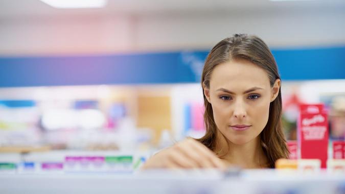 A young woman buying medicine in a pharmacy -The commercial designs displayed in this image represent a simulation of a real product and have been changed or altered enough by our team of retouching and design specialists so that they are free of any copyright infringementshttp://195.