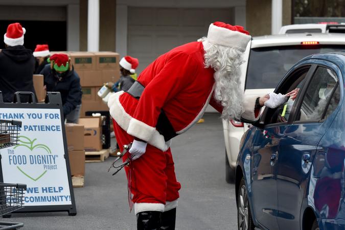 Mandatory Credit: Photo by Aimee Dilger/SOPA Images/Shutterstock (11566852a)A Santa hands candy canes to a guest at the Al Beech food pantry.