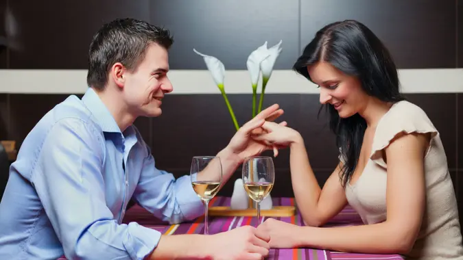 A couple holds hands while drinking wine during dinner.
