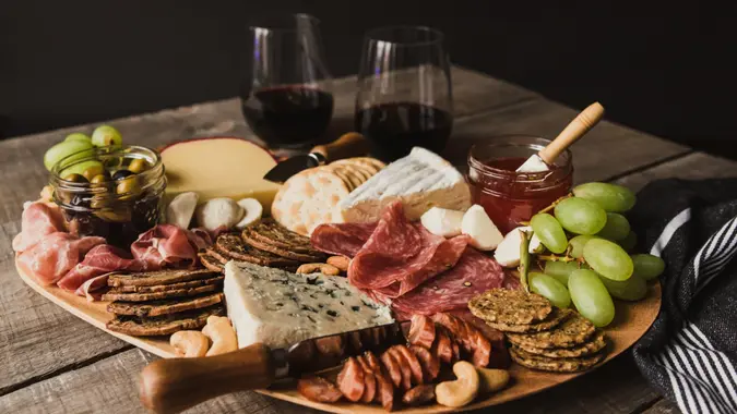 Close up of charcuterie board and glasses of wine on wooden table.