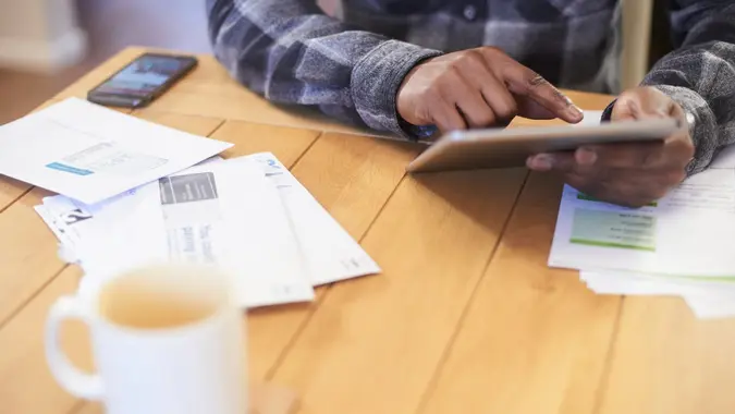 Anonymous hands using a digital tablet to browse the net and ask for better deals.