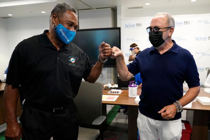 Mandatory Credit: Photo by Lynne Sladky/AP/Shutterstock (11674612a)Former Miami Dolphins football player Nat Moore, 69, left, bumps fists with music producer Emilio Estefan, 67, right, before receiving the Pfizer-BioNTech COVID-19 vaccine at Jackson Memorial Hospital, in Miami.