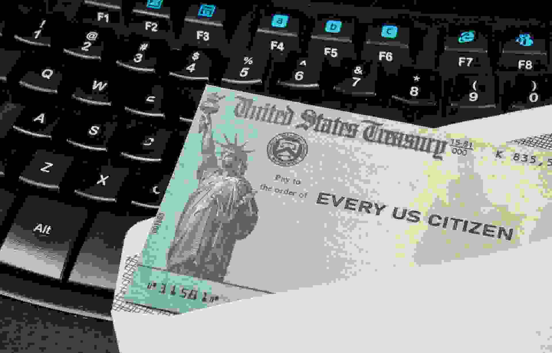 US Treasury concept check to illustrate coronavirus stimulus payment on keyboard used for working from home.