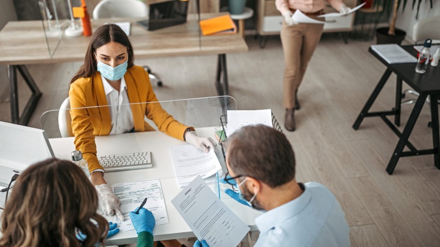 Couple signing a document on a meeting at insurance agent office wearing protective gloves and face mask.