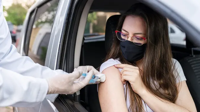 Nurse performing drive-thru immunization.