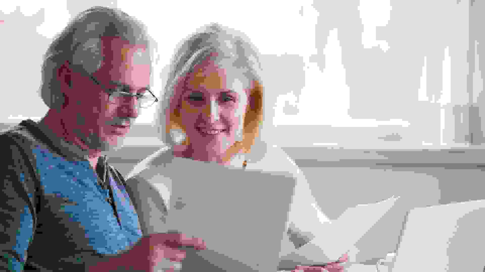 Happy old middle aged couple holding reading good news in document, smiling senior mature family excited by mail letter, checking paying domestic bills online on laptop, discussing budget planning.