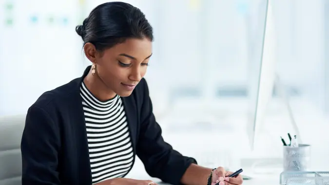 Professional woman going over documents in her office, concentrating on business paperwork and planning.