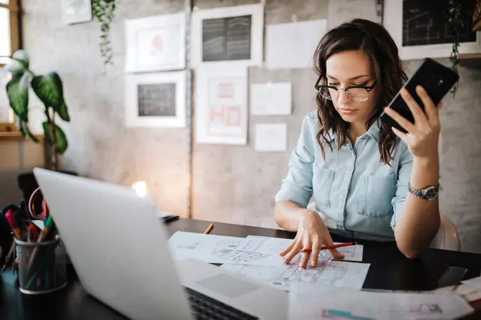 Young female entrepreneur using smart phone at modern working place.