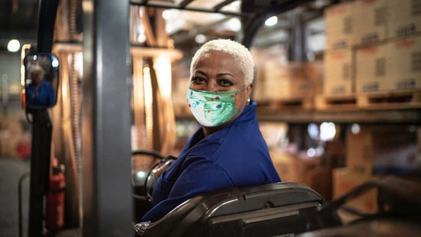 Portrait of female worker driving forklift in warehouse.