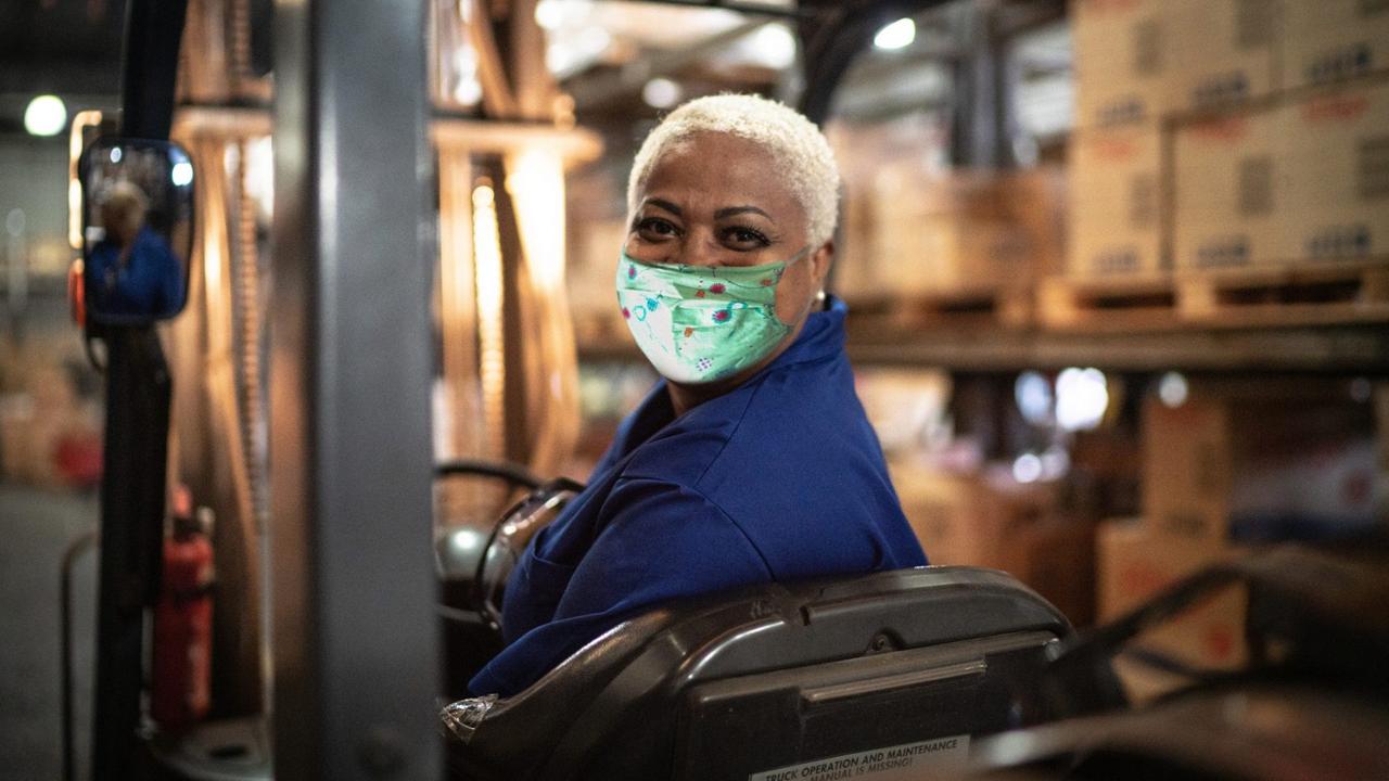 Portrait of female worker driving forklift in warehouse.