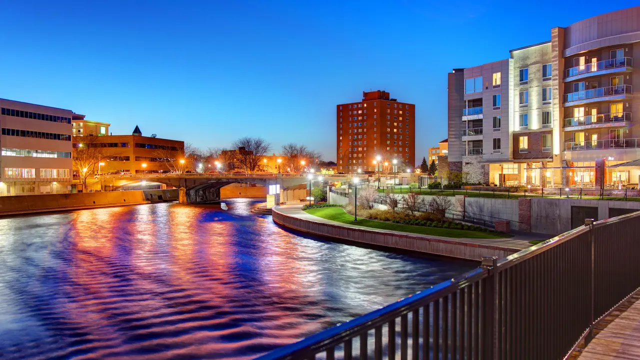 Shot of Sioux Falls, South Dakota at sunrise with colors reflected on the water against lit up buildings