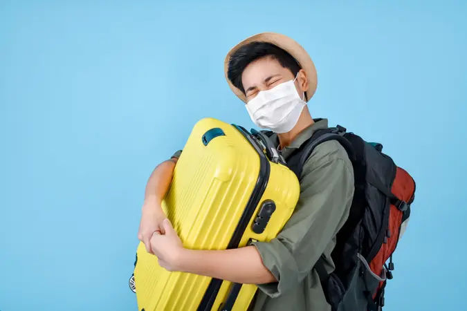 Asian tourists wear masks and carry luggage.