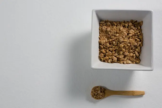 Bowl of grapenuts with spoon on white background.
