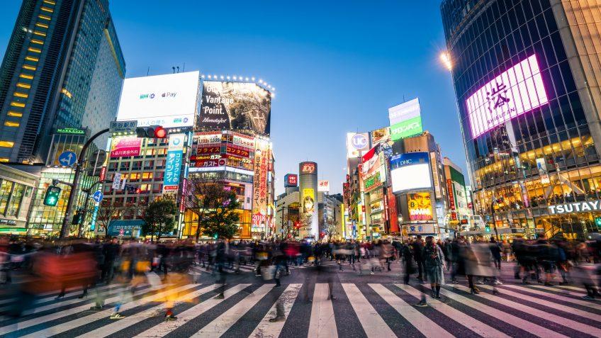 pedestrians walking across with crowded traffic at Shibuya crossing square.