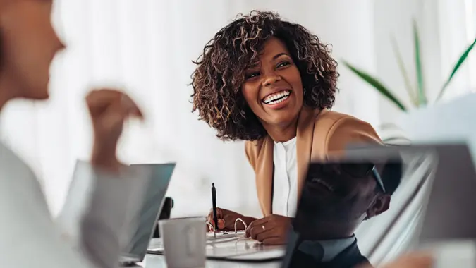 Portrait of cheerful african american businesswoman discussing and smiling at the meeting with colleagues.