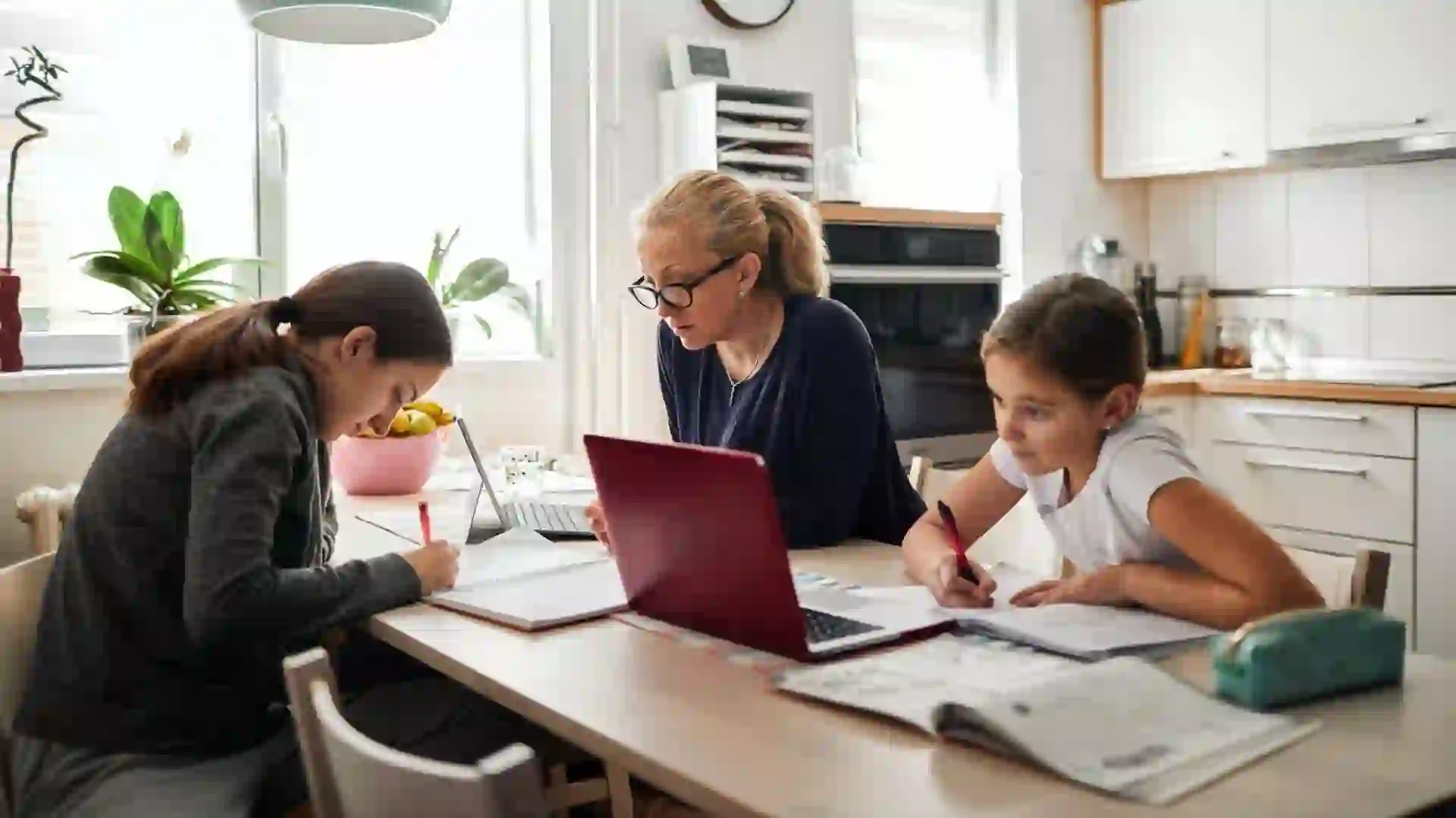 Mother helping her daughters to finish school homework during coronavirus quarantine.