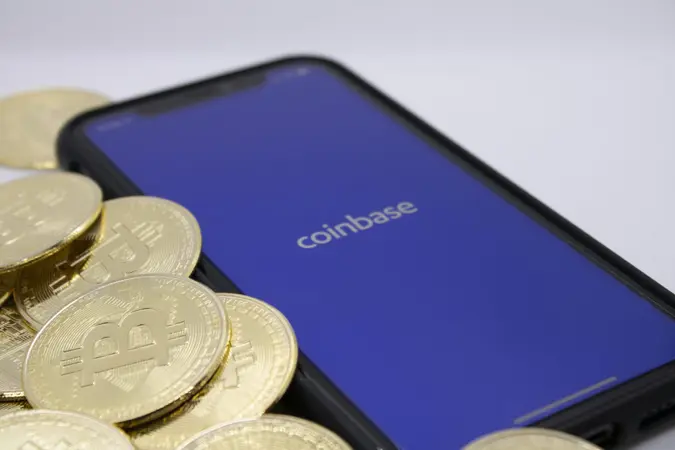 Bitcoins placed beside Coinbase App on iPhone, illustrating one of the largest Bitcoin providers, photographed in Cologne, Germany, 14th of April 2021.