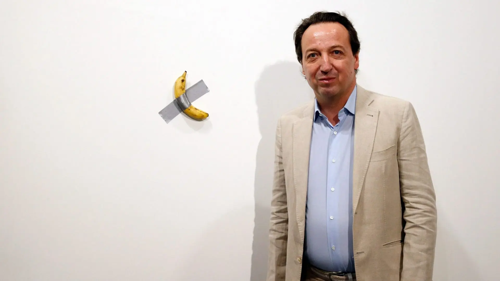 Mandatory Credit: Photo by RHONA WISE/EPA-EFE/Shutterstock (10492891g)Emmanuel Perrotin, founder of the Perrotin Gallery poses with Italian artist Maurizio Cattelan piece's 'Comedian' (a banana duct taped to the wall) during Art Basel in Miami, Florida, USA, 05 December 2019.