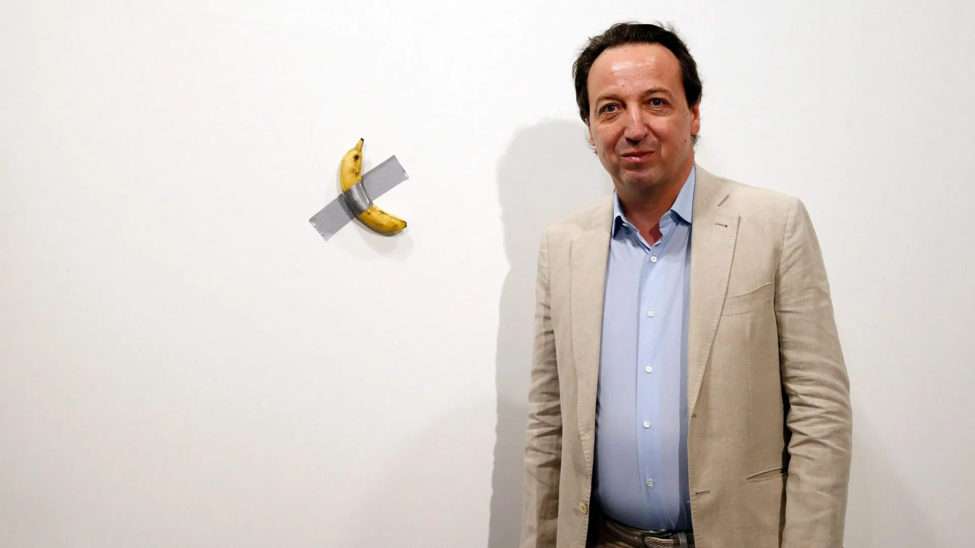 Mandatory Credit: Photo by RHONA WISE/EPA-EFE/Shutterstock (10492891g)Emmanuel Perrotin, founder of the Perrotin Gallery poses with Italian artist Maurizio Cattelan piece's 'Comedian' (a banana duct taped to the wall) during Art Basel in Miami, Florida, USA, 05 December 2019.