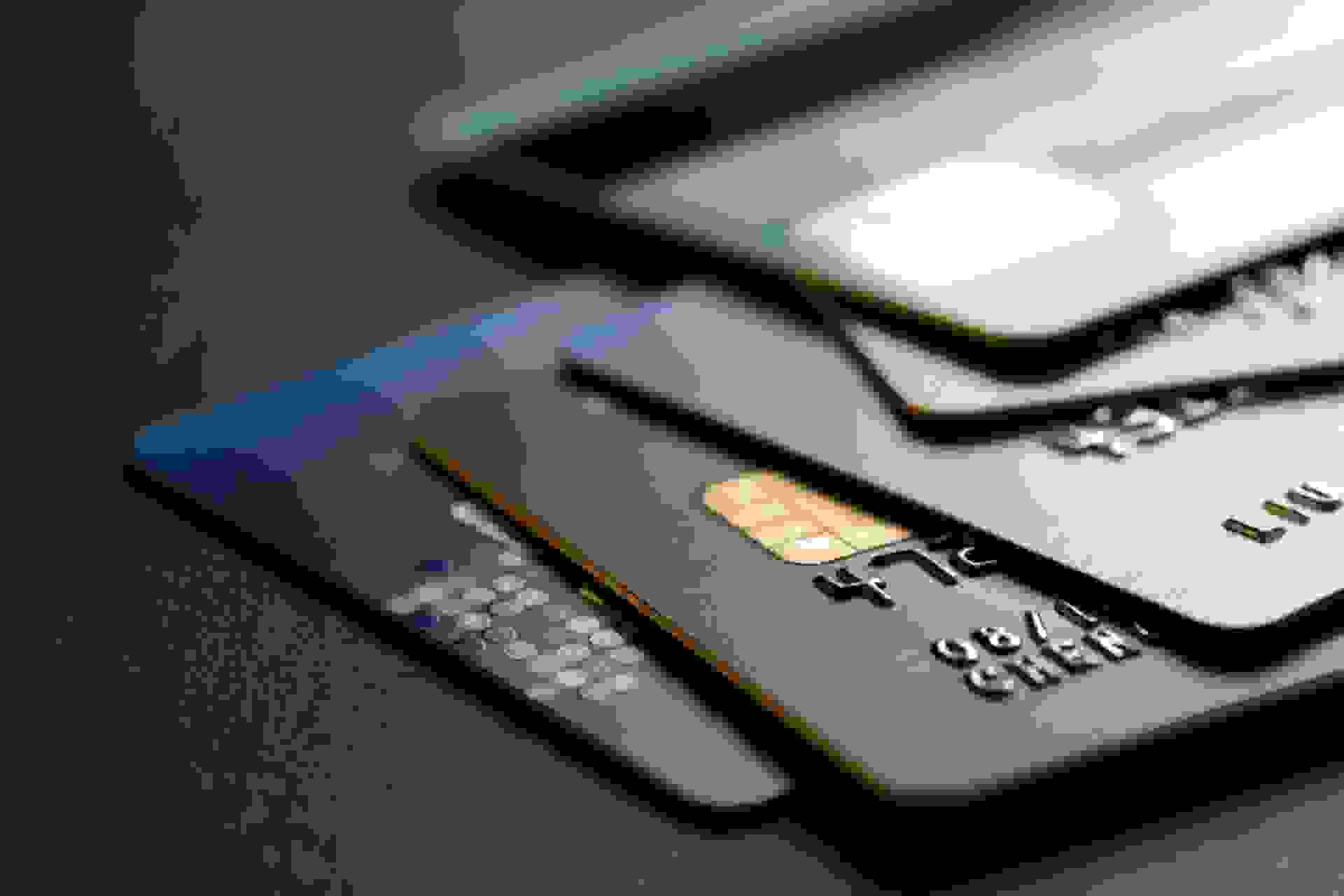 stack of multicolored credit cards on black background.