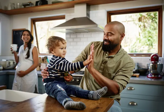 Shot of a young man giving his adorable child a high five at home.