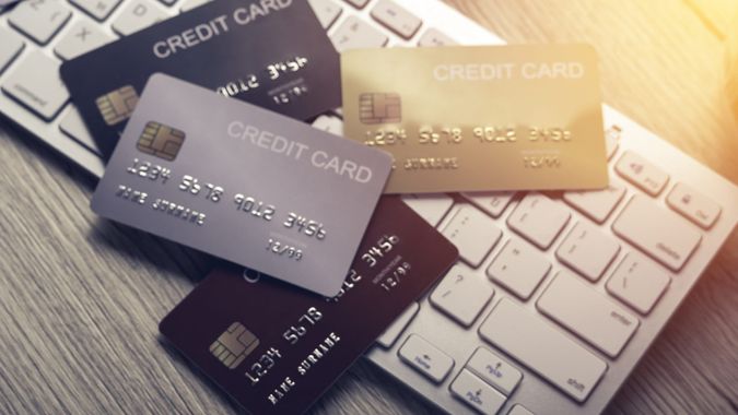 many mockup credit card above white tablet keyboard on an office wooden table top view.