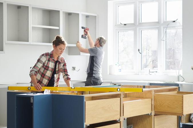 a female kitchen fitting cupboards for worktop.