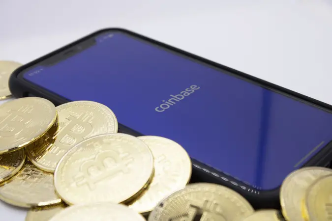 Bitcoins placed beside Coinbase App on iPhone, illustrating one of the largest Bitcoin providers, photographed in Cologne, Germany, 14th of April 2021.