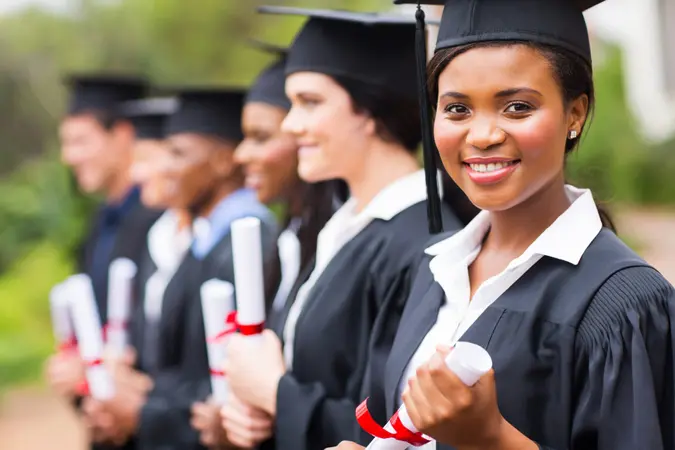 pretty african female college graduate at graduation with classmates.