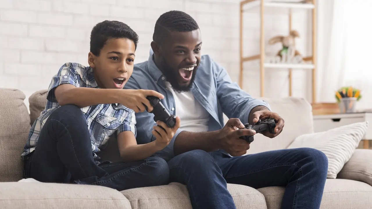 Cheerful Black Father And Son Competing In Video Games At Home stock photo