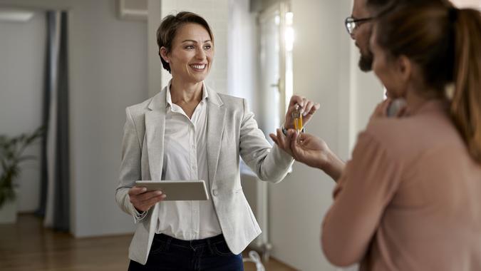 Happy real estate agent giving to a couple keys of their new home. stock photo