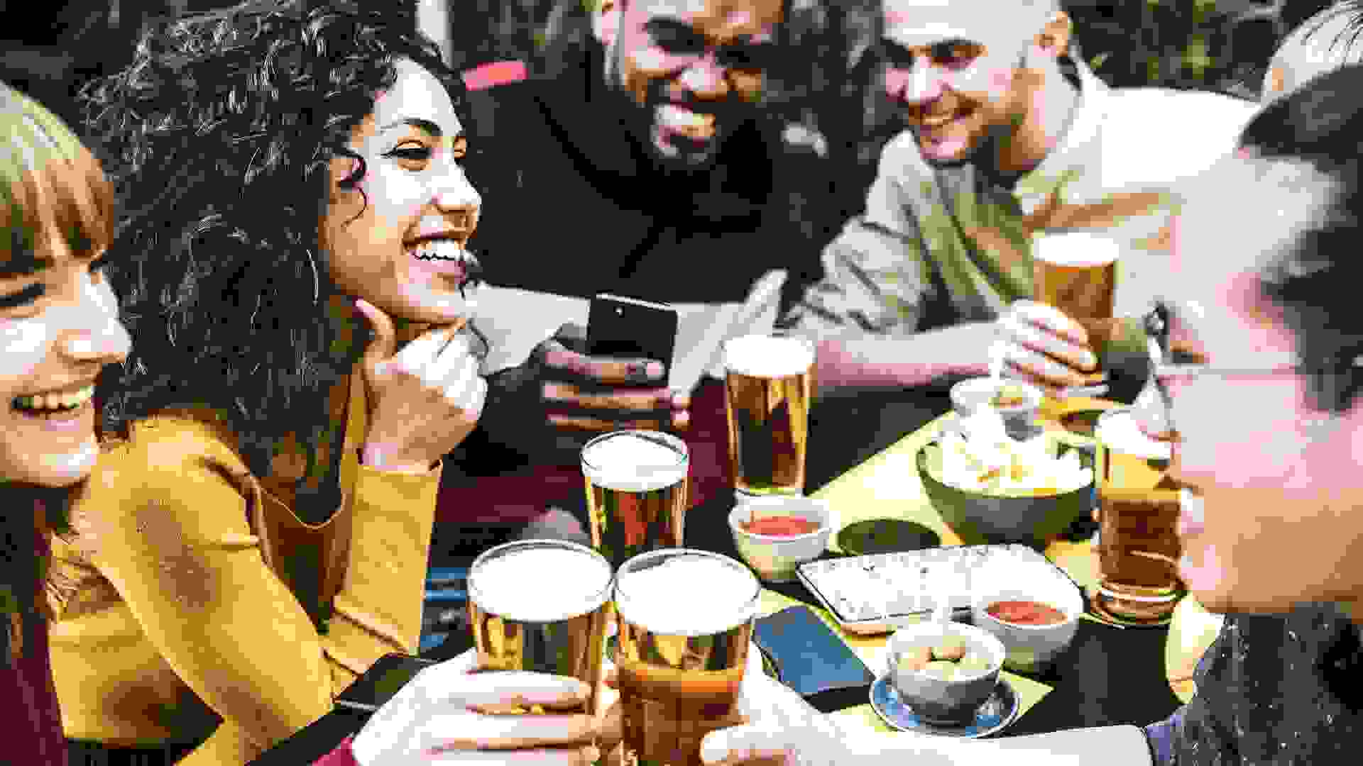 Happy diverse friends drinking beer at brewery pub - Group of young people having fun together at backyard home party - Friendship concept stock photo