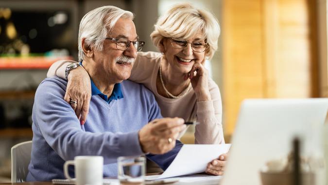 Happy mature couple using laptop while planning their home budget. stock photo